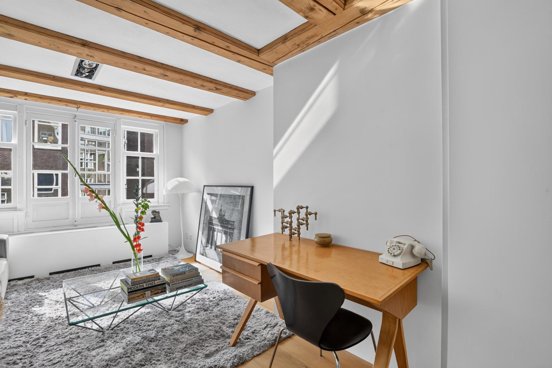 Woonkamer met bureau en ramen naar de Haarlemmerstraat, een appartement in het centrum van Amsterdam